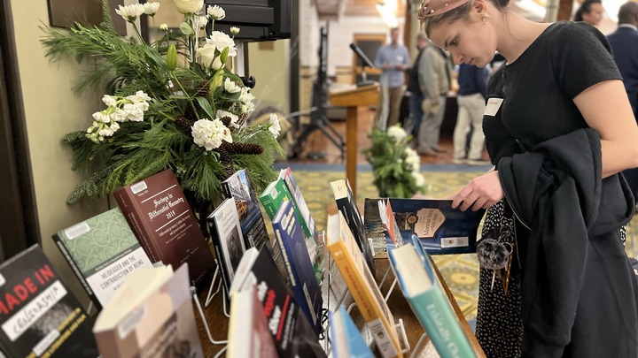 A woman reads from a book at a table containing published Lehigh faculty author books