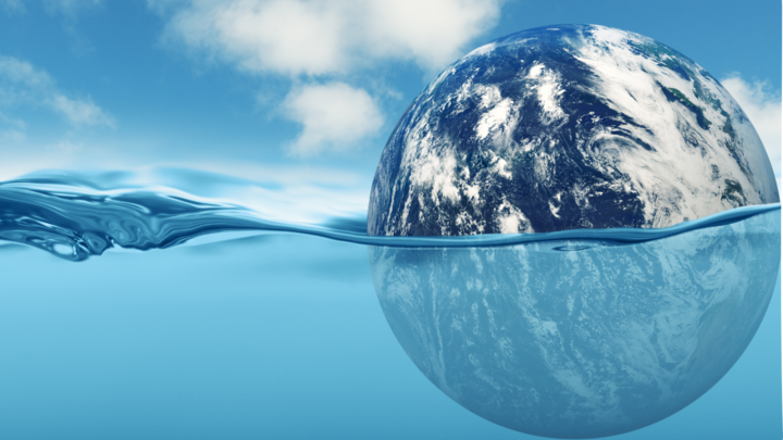 earth halfway submerged in an ocean with blue sky and clouds behind