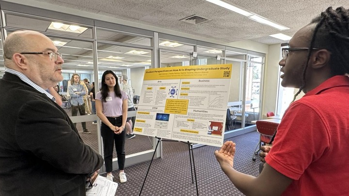 Instructor speaking with student at a poster session