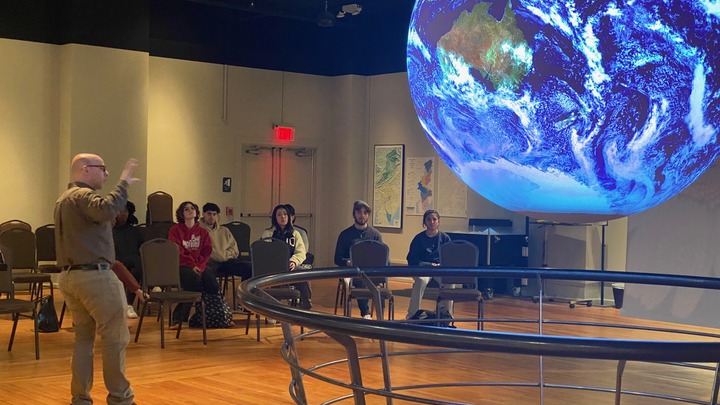 Students listening to a presentation with a digital projection globe