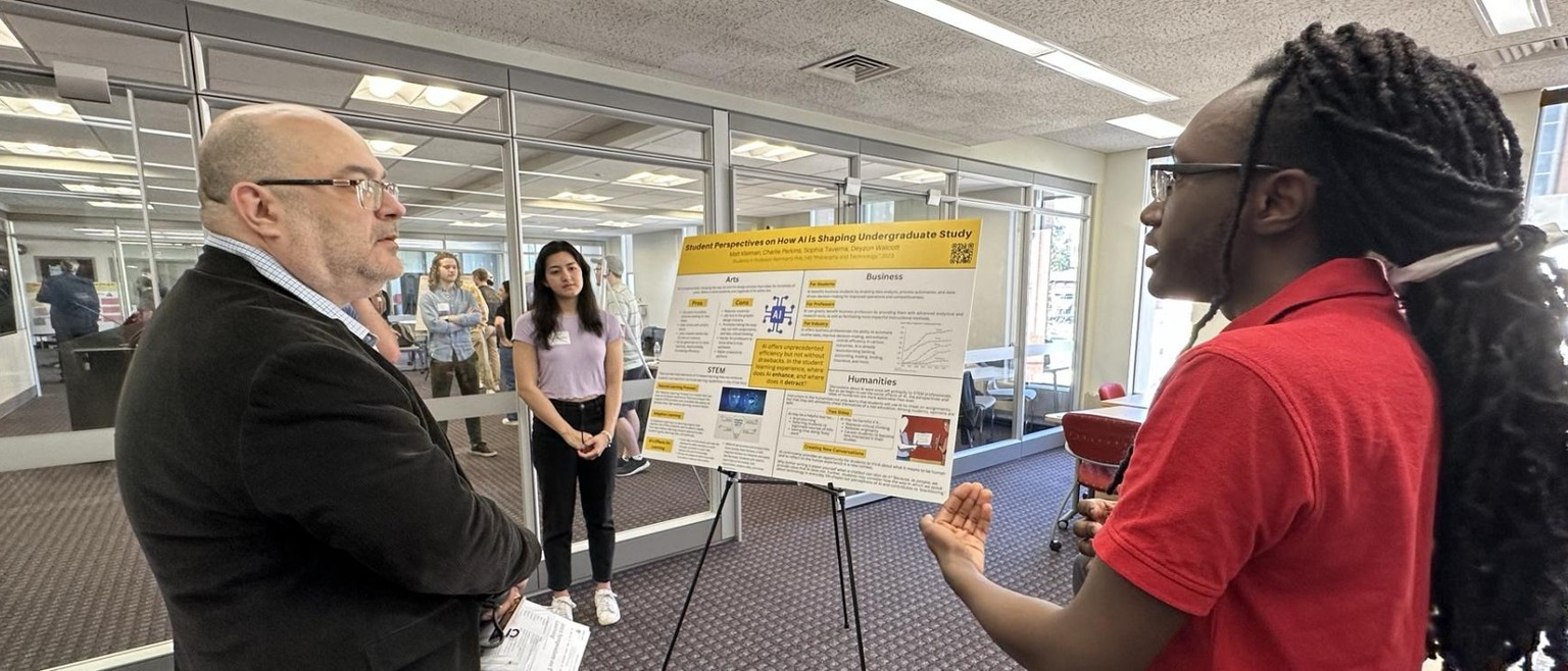 Instructor speaking with student at a poster session