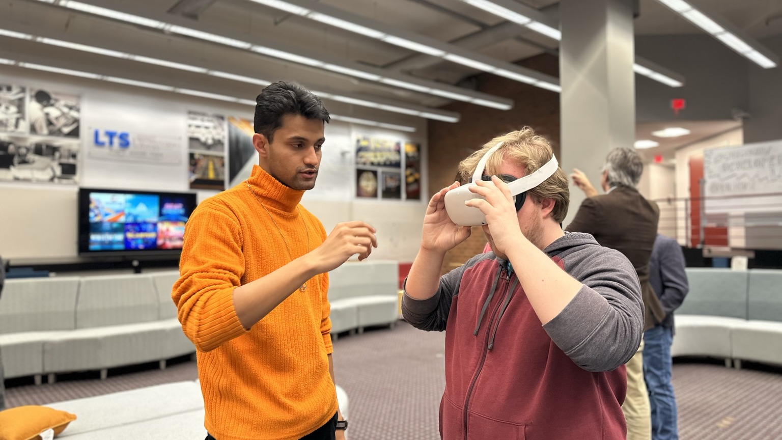 Graduate student assists another student with VR equipment at Student Developer Lab Open House